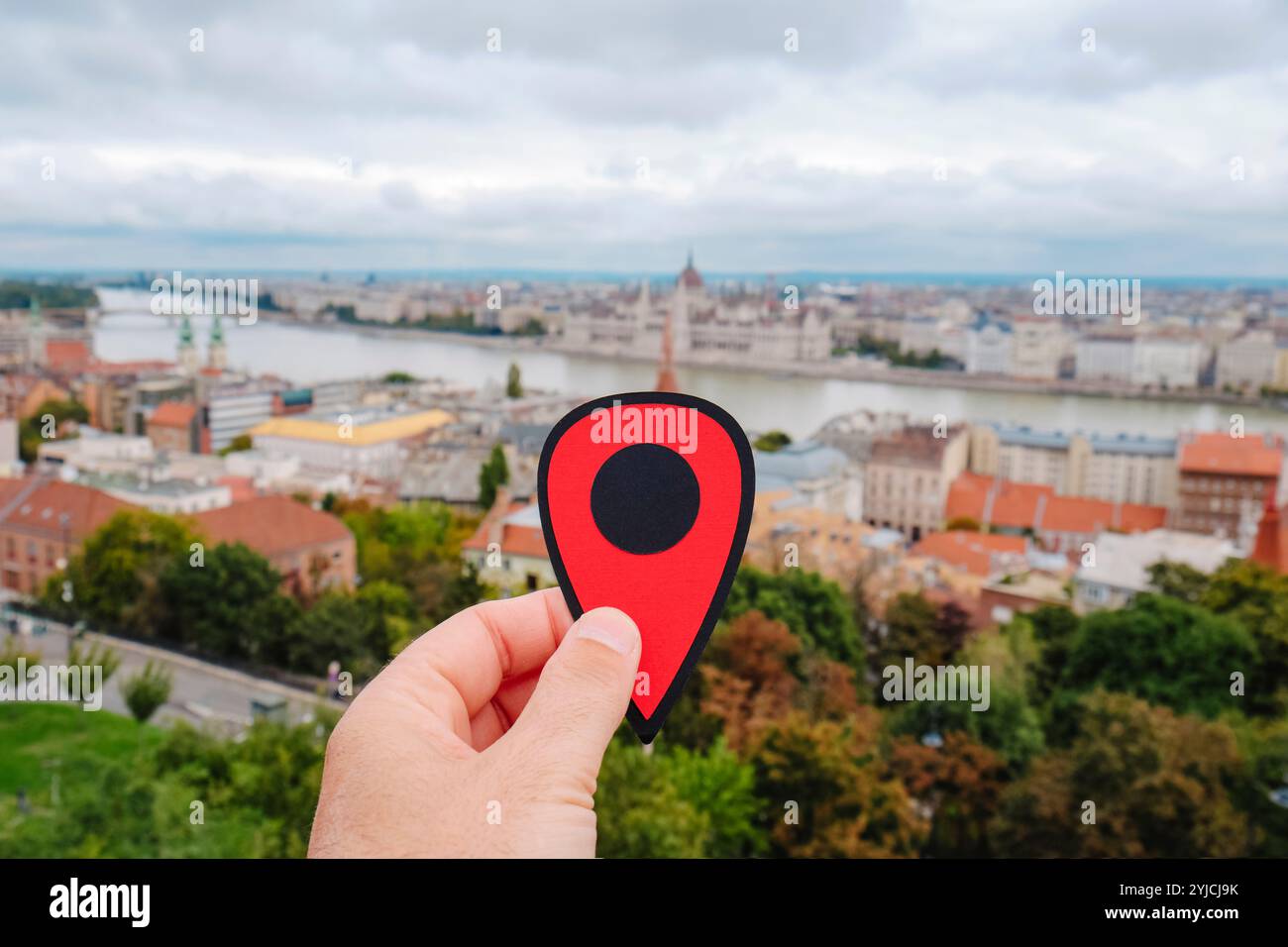primo piano della mano di un uomo che tiene un segno rosso nel Danubio a Budapest, Ungheria, con Buda in primo piano e Pest nell'altro riverside Foto Stock