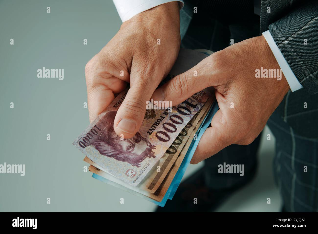 primo piano di un uomo d'affari, in un elegante abito grigio, con alcune note di fiorino ungheresi in piedi all'interno Foto Stock