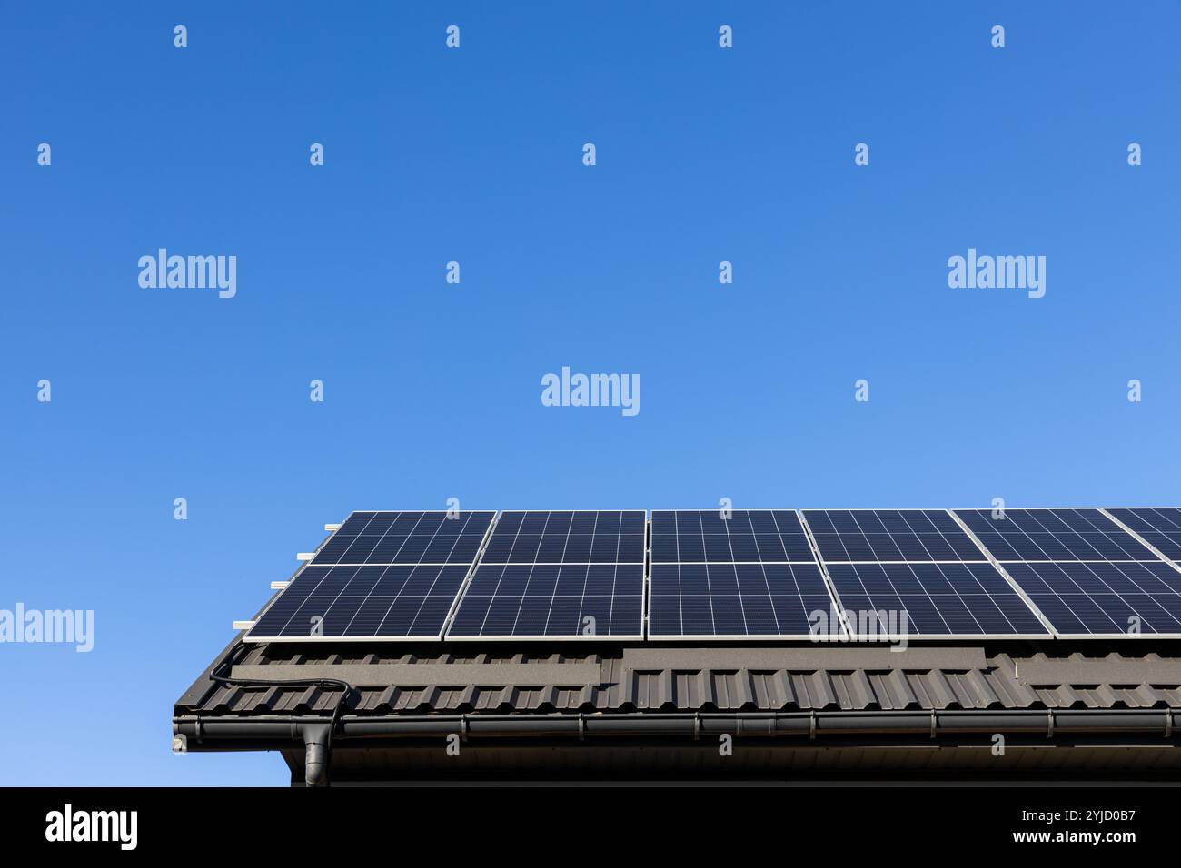 Casa con impianto fotovoltaico a pannelli solari installata professionalmente su tetto in lamiera, verde. Sfondo blu chiaro del cielo. Alternativa pulita Foto Stock