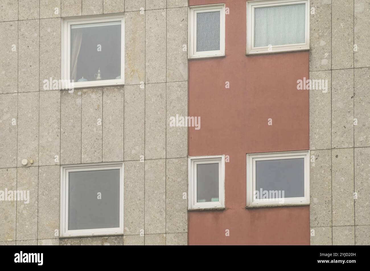 La facciata geometrica di un edificio residenziale presenta un mix di pannelli e finestre in cemento, creando uno schema visivamente suggestivo Foto Stock
