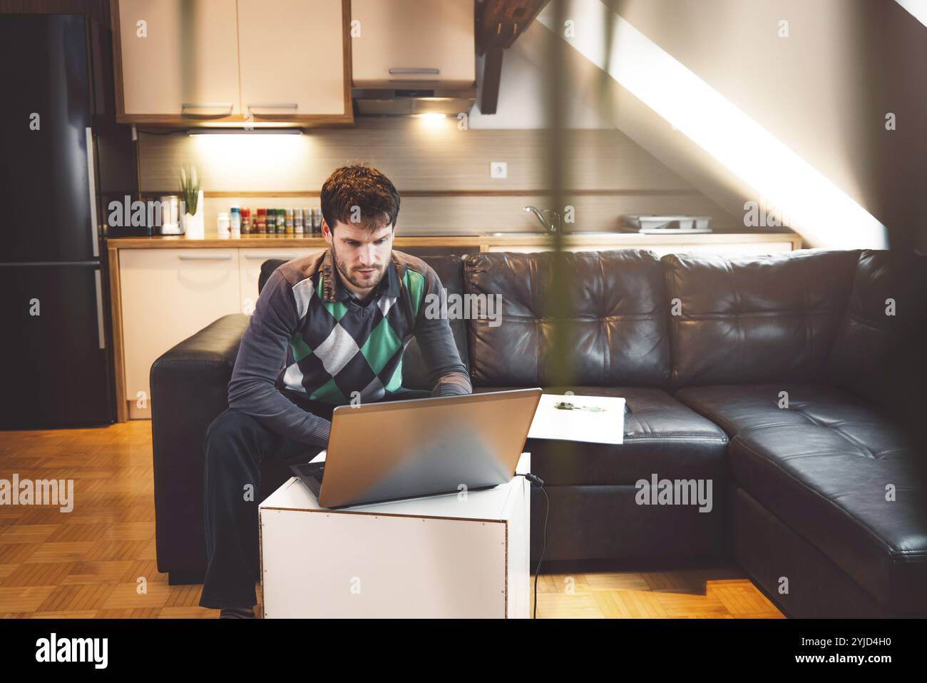 Sorridente uomo caucasico freelancer che usa laptop che studia online lavorando da casa, felice ragazzo millennial casuale che scrive su laptop che naviga su Internet guardando Foto Stock