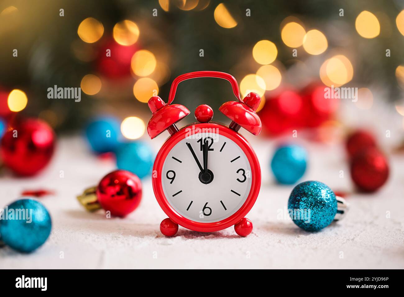 Natale. Sveglia e ornamenti di natale rossi e blu su un tavolo bianco. Foto Stock