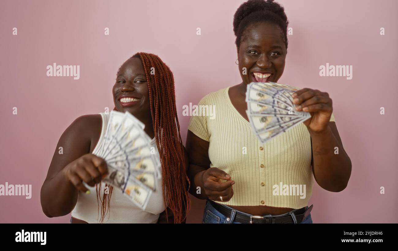 Due donne afroamericane sorridono e ci tengono in mano banconote da un dollaro su sfondo rosa, mostrando amore e gioia Foto Stock