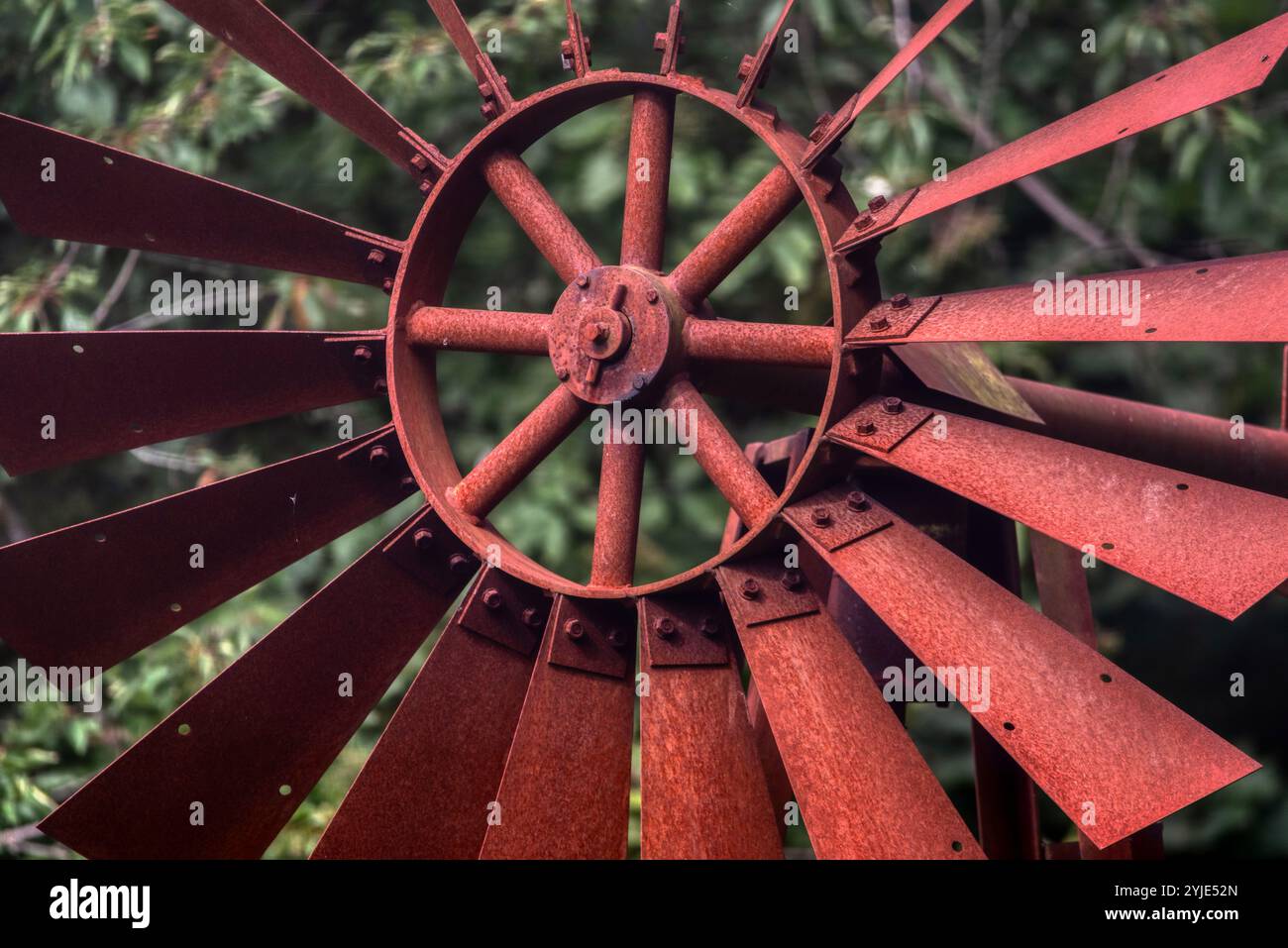 Mulino a vento fatto in casa dipinto di rosso usato come decorazione da cortile. Un piccolo mulino a vento di colore rosso dipinto luminoso si trova in un cortile anteriore Foto Stock