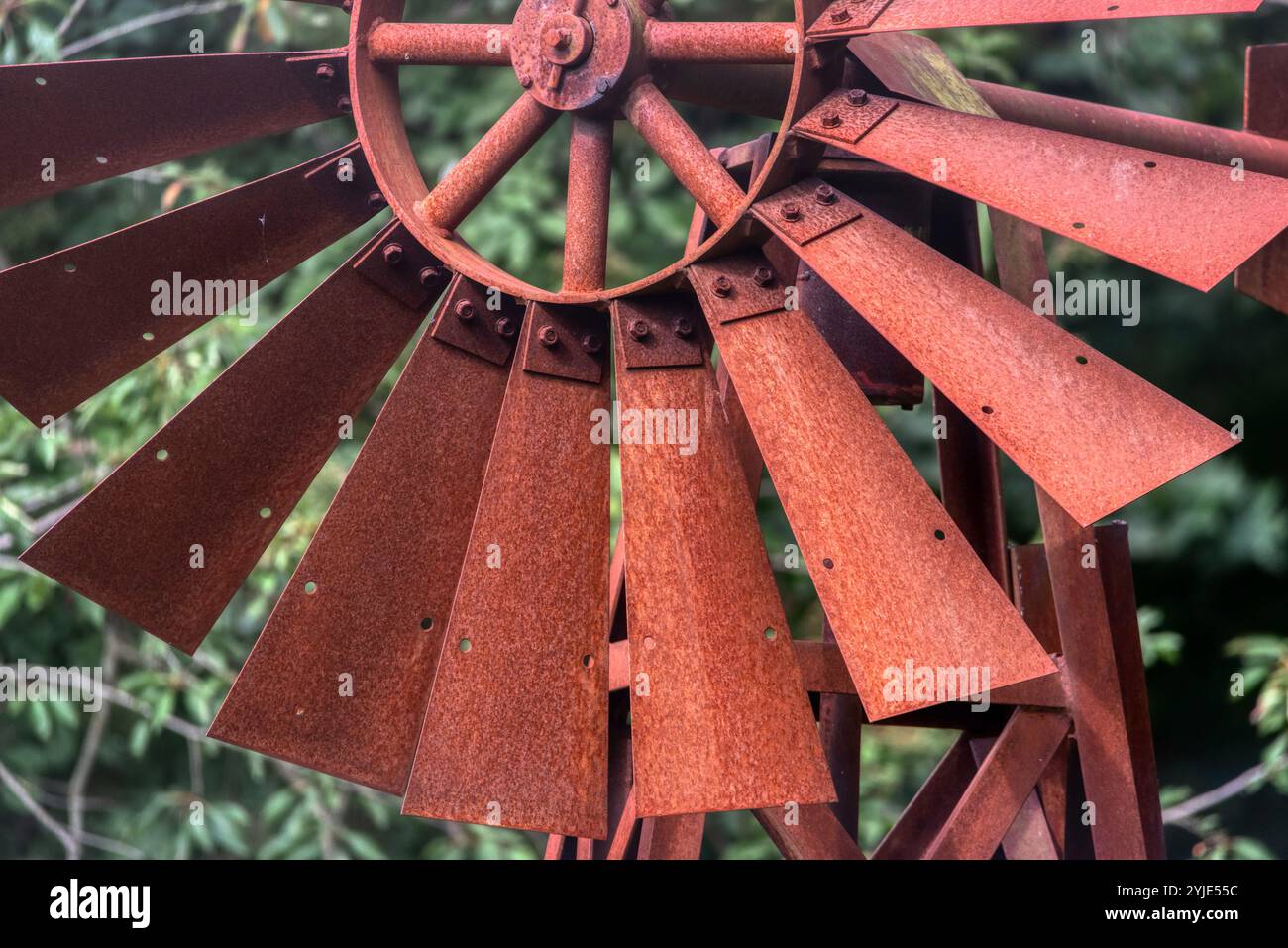 Mulino a vento fatto in casa dipinto di rosso usato come decorazione da cortile. Un piccolo mulino a vento di colore rosso dipinto luminoso si trova in un cortile anteriore Foto Stock