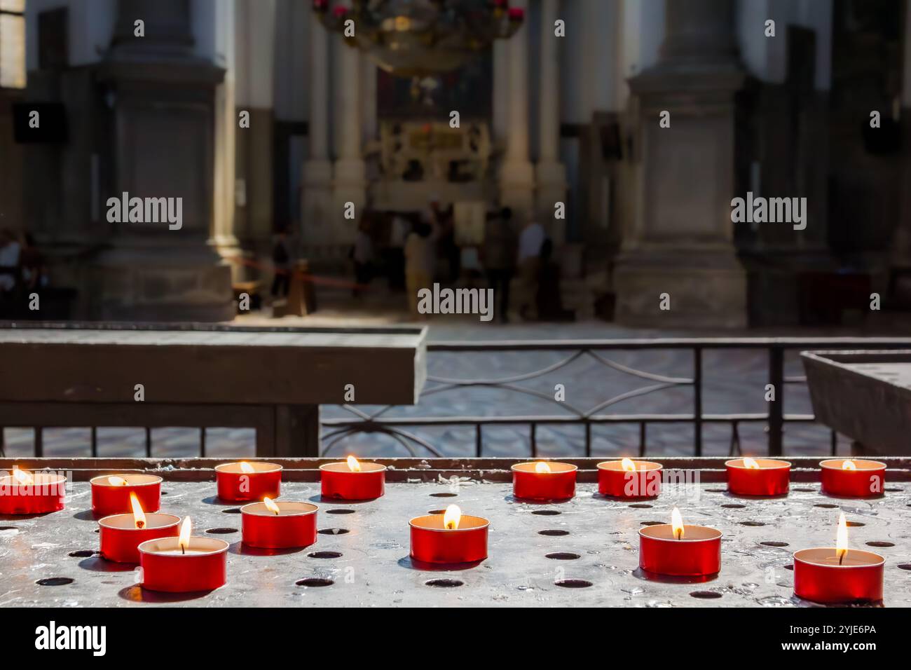 Cera rossa che prega candele nella chiesa cattolica romana Foto Stock