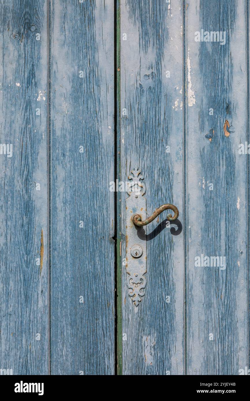 Antica porta blu-verde logorata e maniglia arrugginita, dettagli architettonici esterni Foto Stock