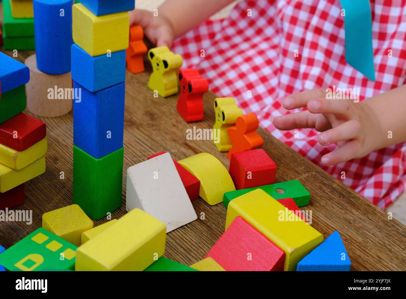 la ragazza gioca giochi di ruolo con figurine in legno, figure, blocchi, giochi per l'asilo, concetto di infanzia, sviluppo precoce dei bambini, creatività, Foto Stock