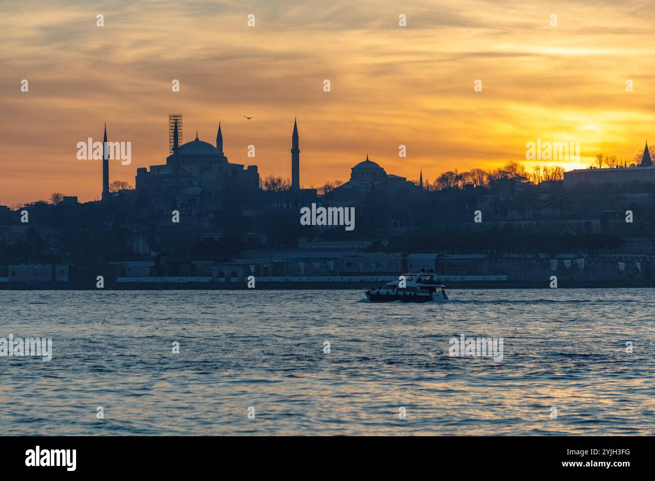 Splendido tramonto alla sagoma del minareto della moschea del Bosforo, barche sull'acqua nella zona Sultanahmet di Istanbul in Turchia Foto Stock