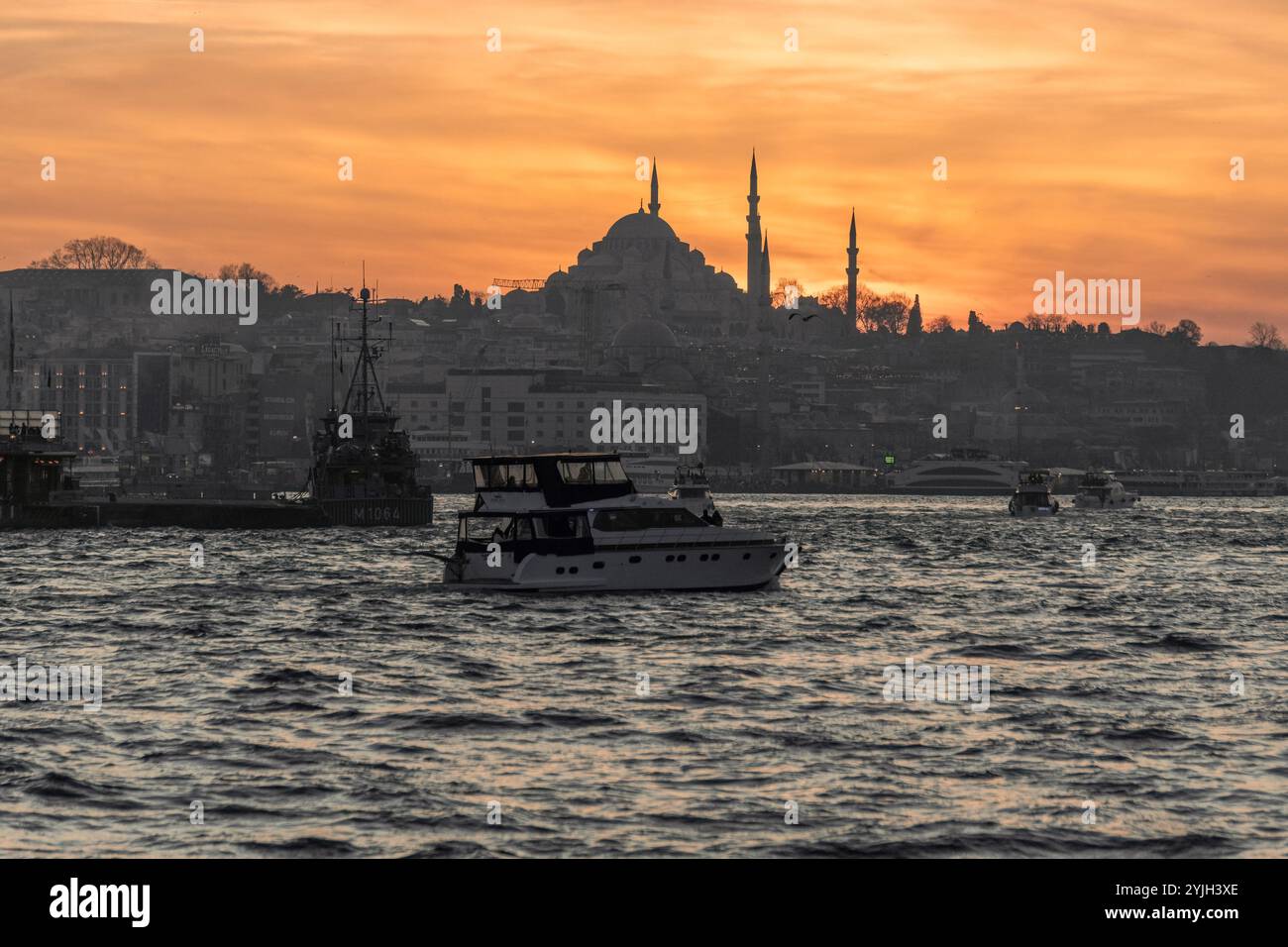 Splendido tramonto alla sagoma del minareto della moschea del Bosforo, barche sull'acqua nella zona Sultanahmet di Istanbul in Turchia Foto Stock