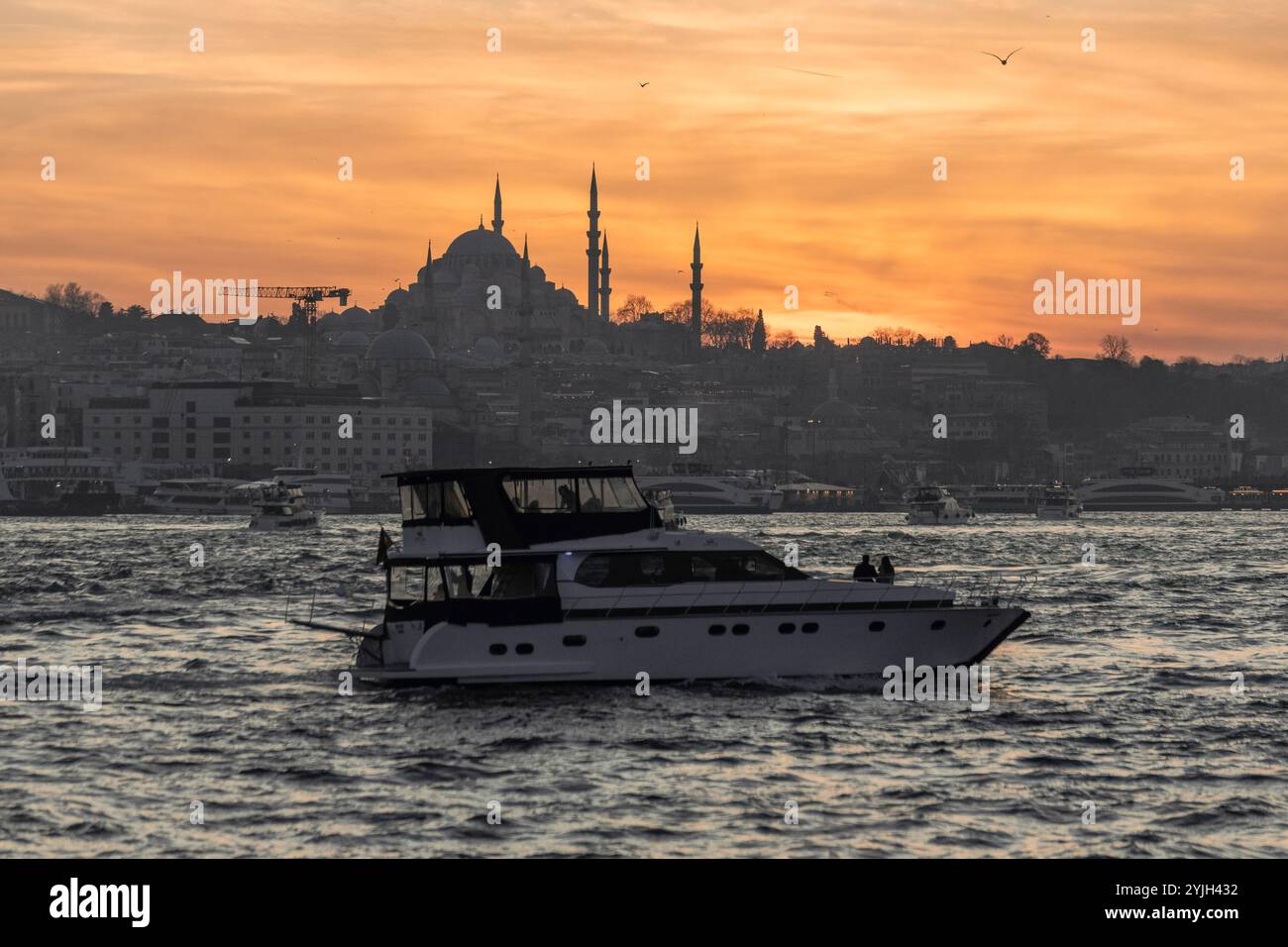 Splendido tramonto alla sagoma del minareto della moschea del Bosforo, barche sull'acqua nella zona Sultanahmet di Istanbul in Turchia Foto Stock