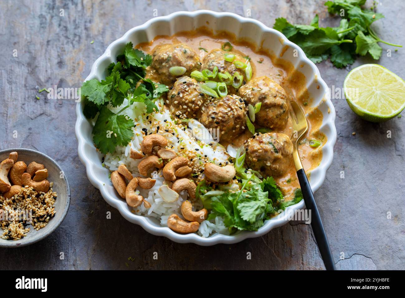 Polpette di tacchino in salsa tailandese al curry con riso, coriandolo e anacardi Foto Stock