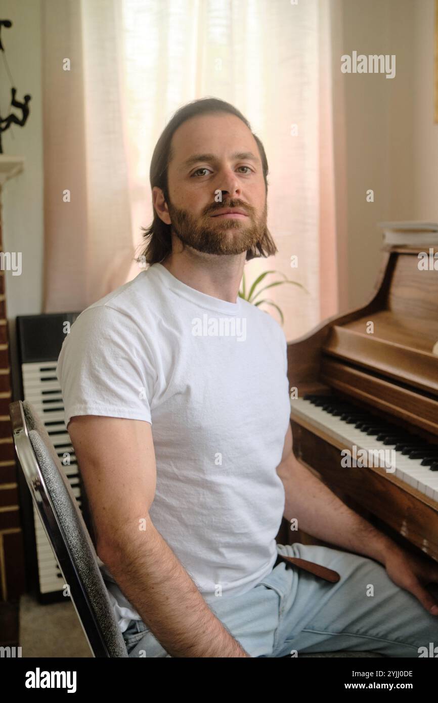 Giovane che compone musica su piano nel salotto in stile retrò Foto Stock