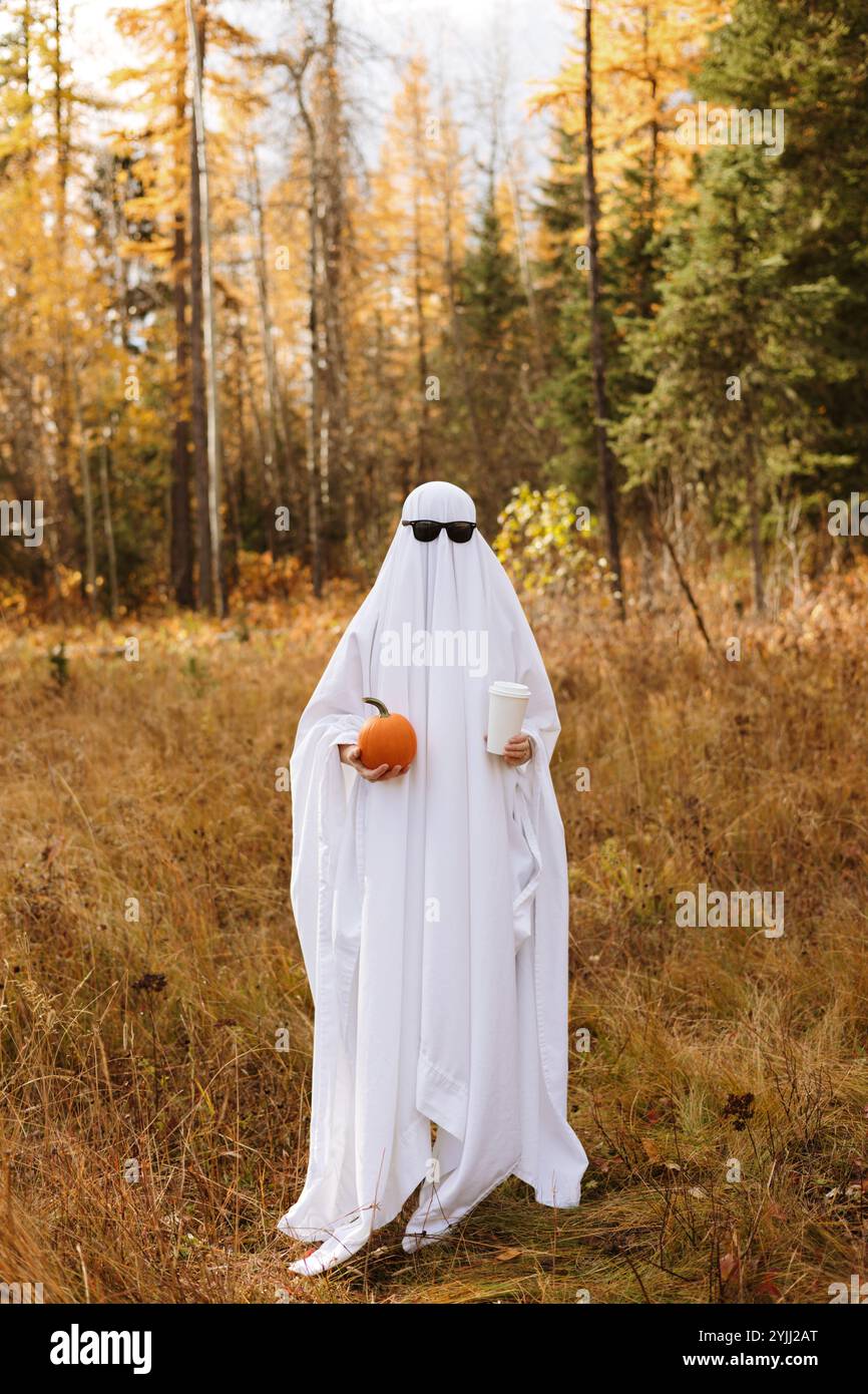 Persona in piedi in costume fantasma con zucca e caffè e. Foto Stock