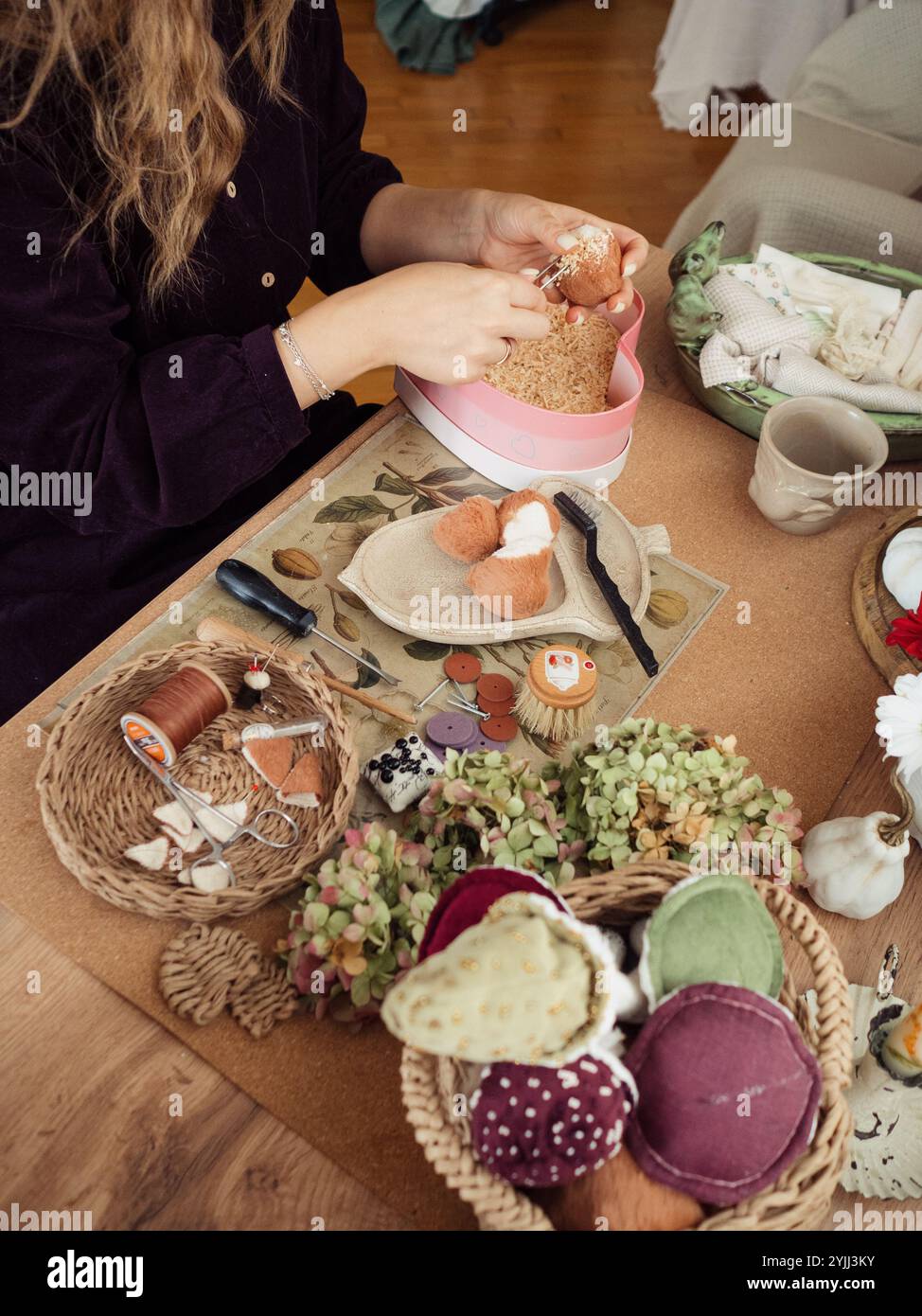 Donna che stuffa Teddy Fox con Sawdust alla sua scrivania accogliente Foto Stock