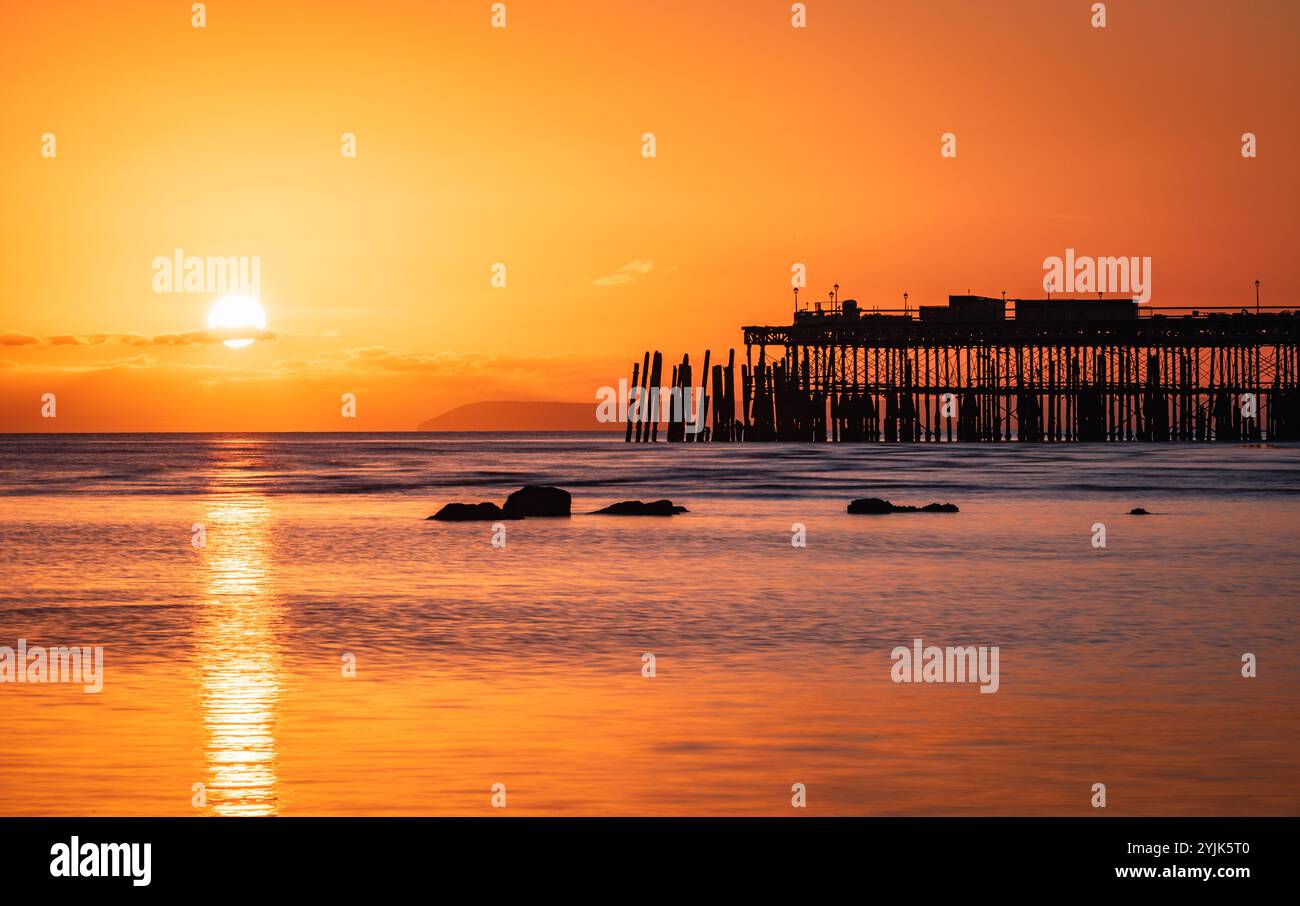 Tramonto con la bassa marea sul lungomare di Hastings, nell'est del Sussex, nell'Inghilterra sud-orientale, Regno Unito Foto Stock