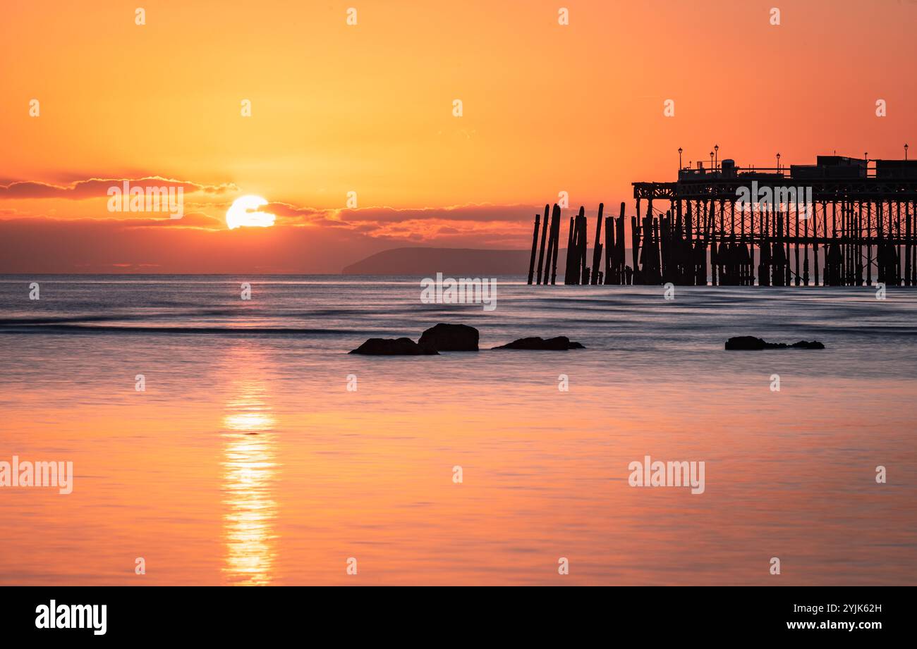 Tramonto con la bassa marea sul lungomare di Hastings, nell'est del Sussex, nell'Inghilterra sud-orientale, Regno Unito Foto Stock