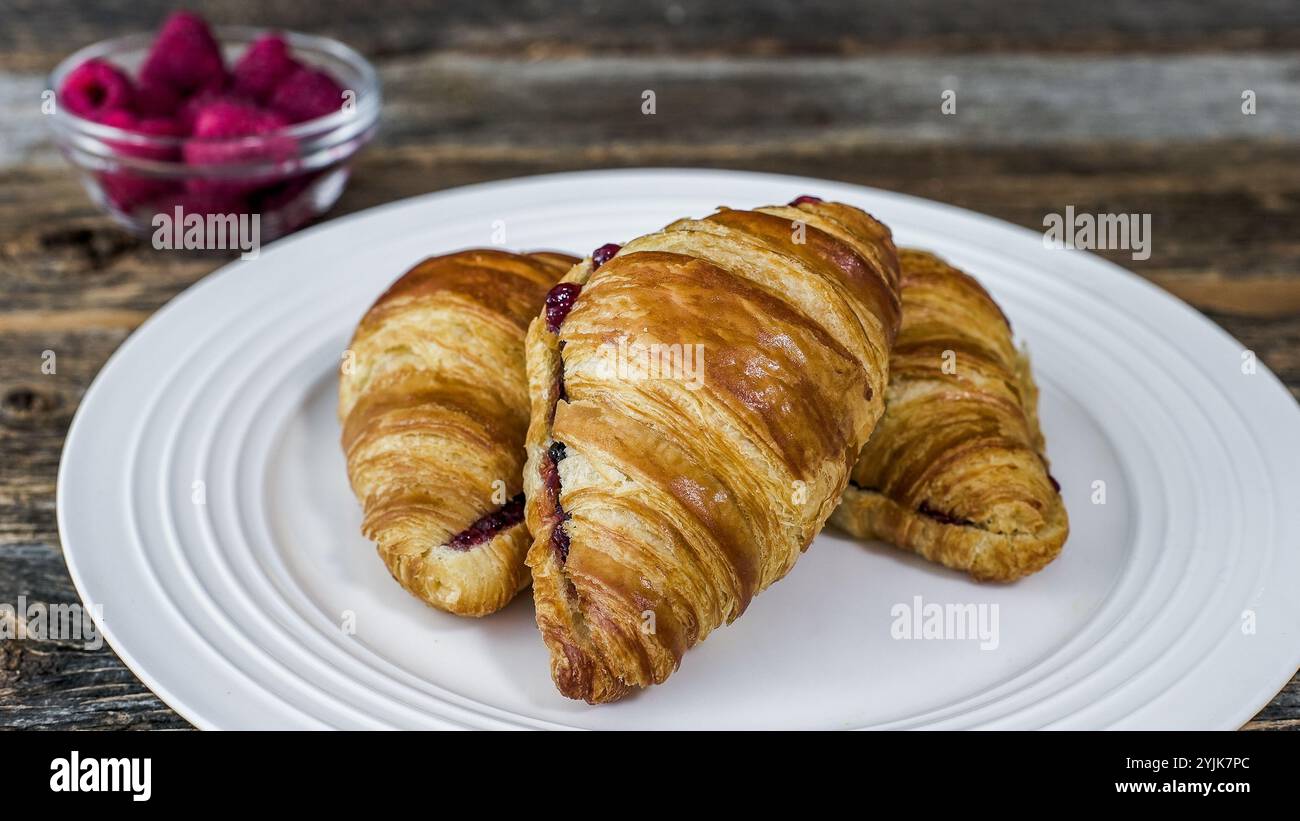 Un piatto bianco con tre croissant ripieni di marmellata. Foto Stock