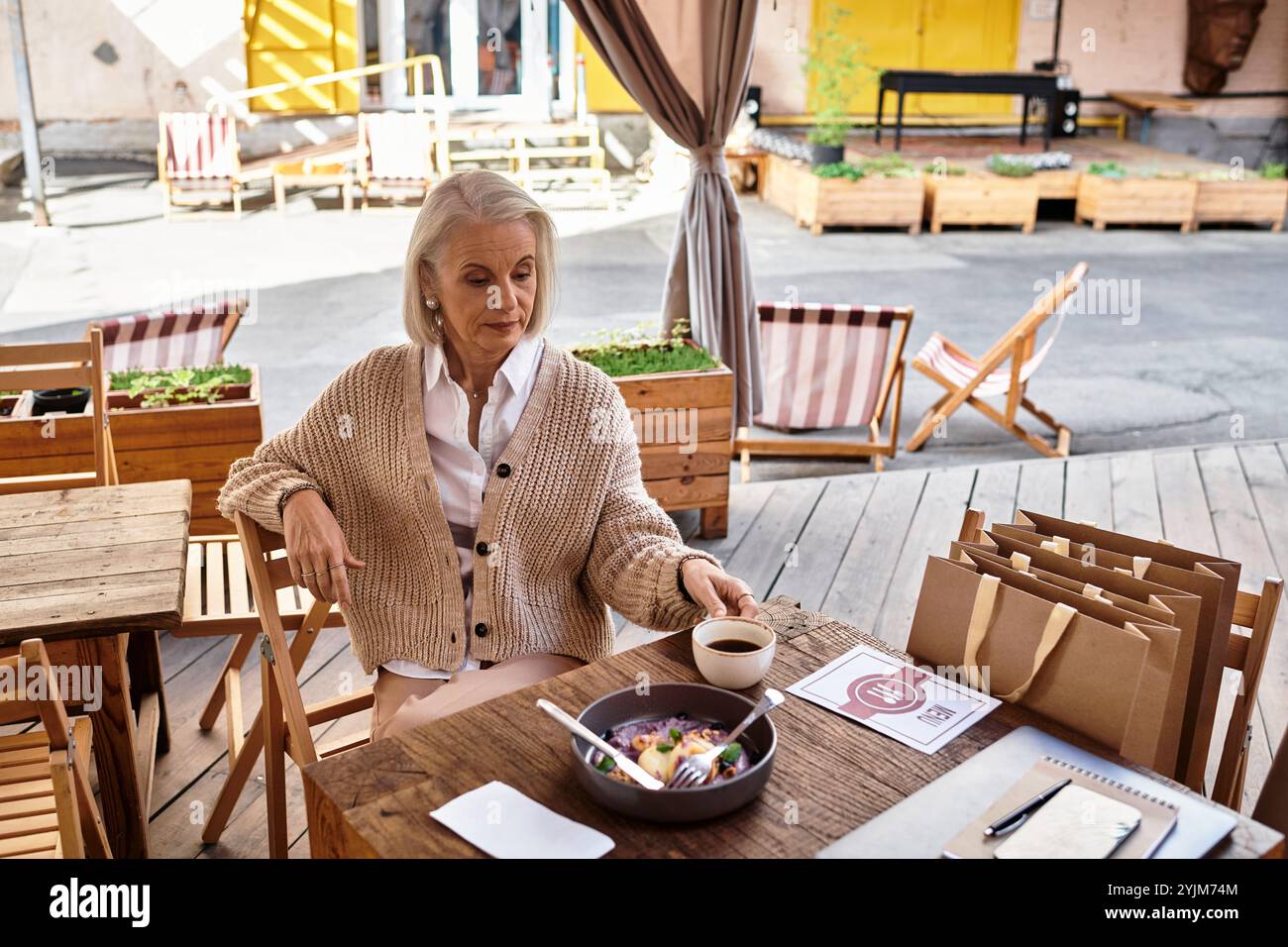 Un momento delizioso catturato mentre una donna gusta il suo pasto in un affascinante ambiente all'aperto. Foto Stock