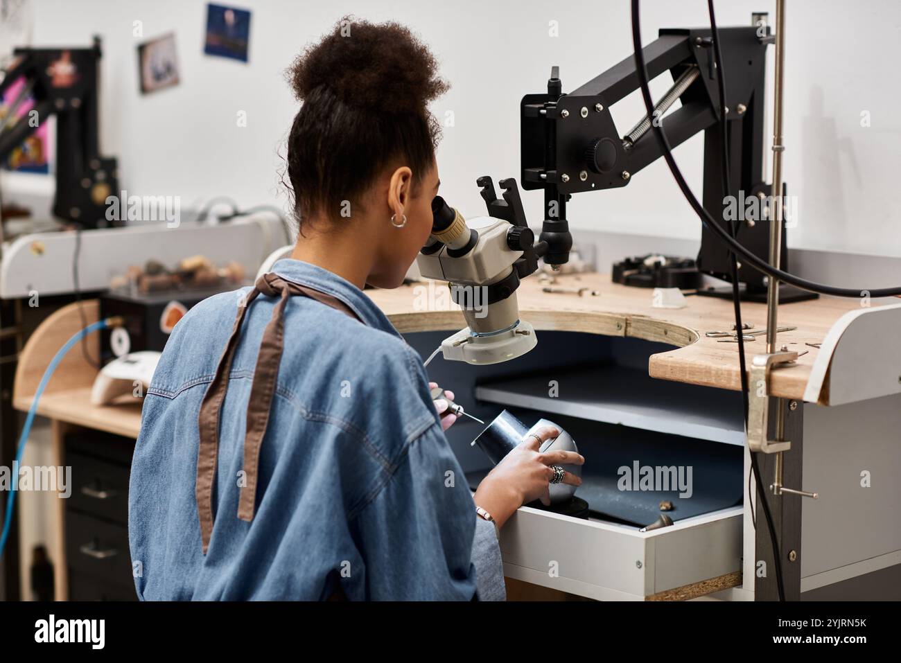Un artigiano dedicato si concentra sulla progettazione di splendidi gioielli utilizzando utensili specializzati. Foto Stock