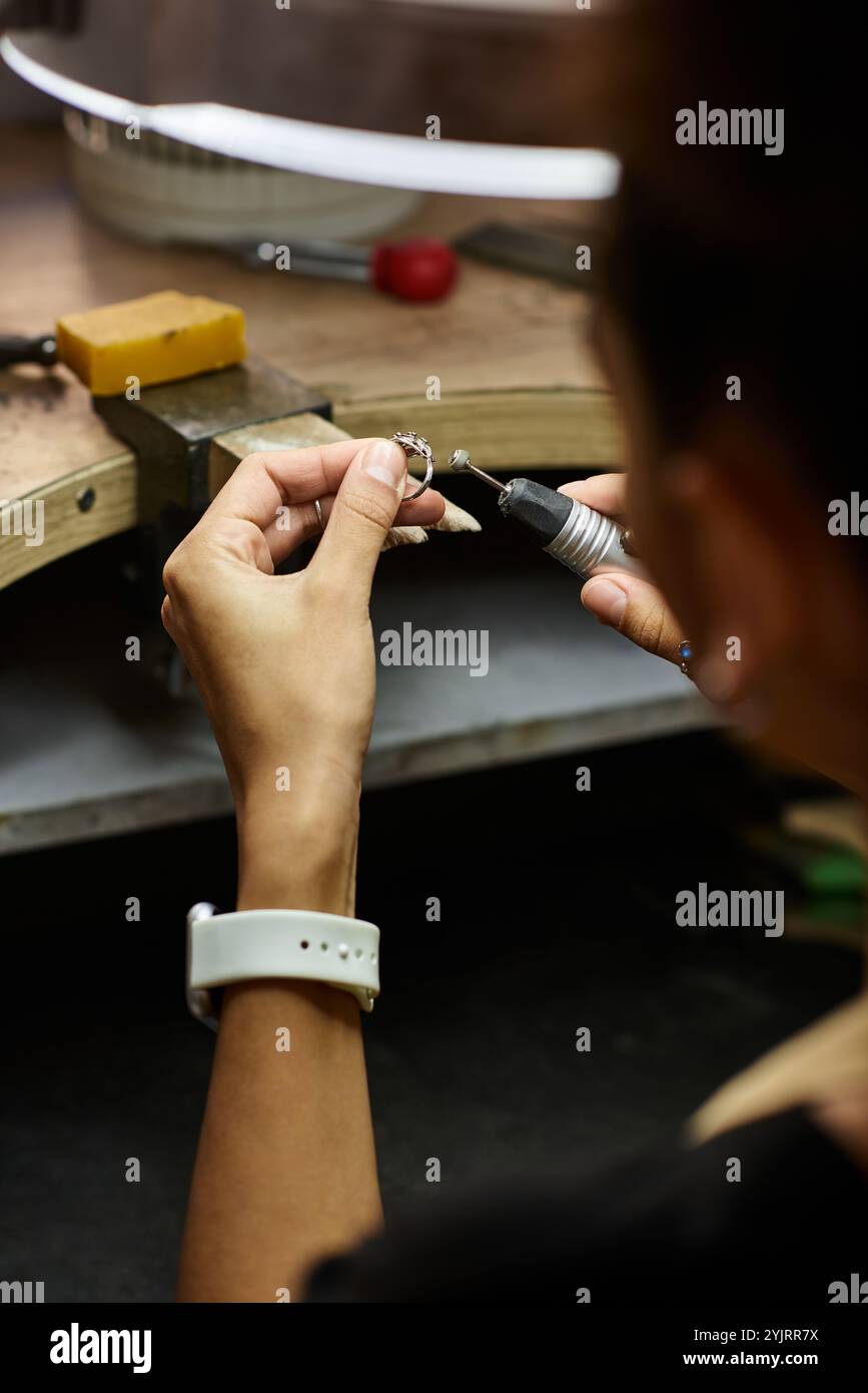 Una donna di talento si concentra sulla creazione di splendidi gioielli con dettagli intricati. Foto Stock