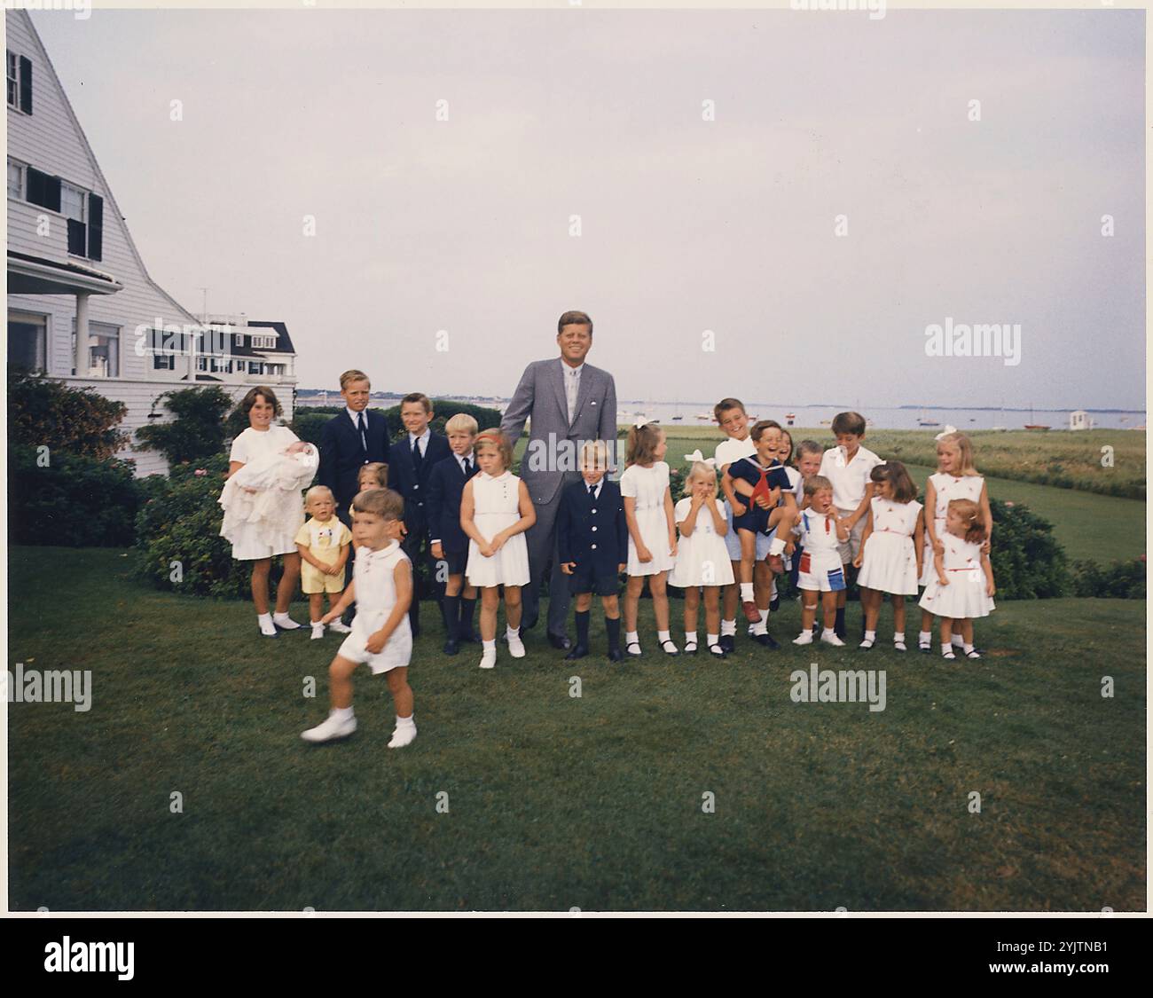 Hyannisport Weekend - il presidente Kennedy con i bambini. Kathleen Kennedy ( Holding Christopher Kennedy ) Edward Kennedy Jr., Joseph P. Kennedy II, Kara Kennedy, Robert F. Kennedy Jr., David Kennedy, Caroline Kennedy, President Kennedy, Michael Kennedy, Courtney Kennedy, Kerry Kennedy, Bobby Shriver ( Holding Timothy Shriver ), Maria Shriver, Steve Smith Jr., Willie Smith, Christopher Lawford, Victoria Lawford, Sidney Lawford, Robin Lawford (in primo piano - John F. Kennedy Jr.). Hyannisport, Massachusetts, Kennedy Compound 1961 Foto Stock