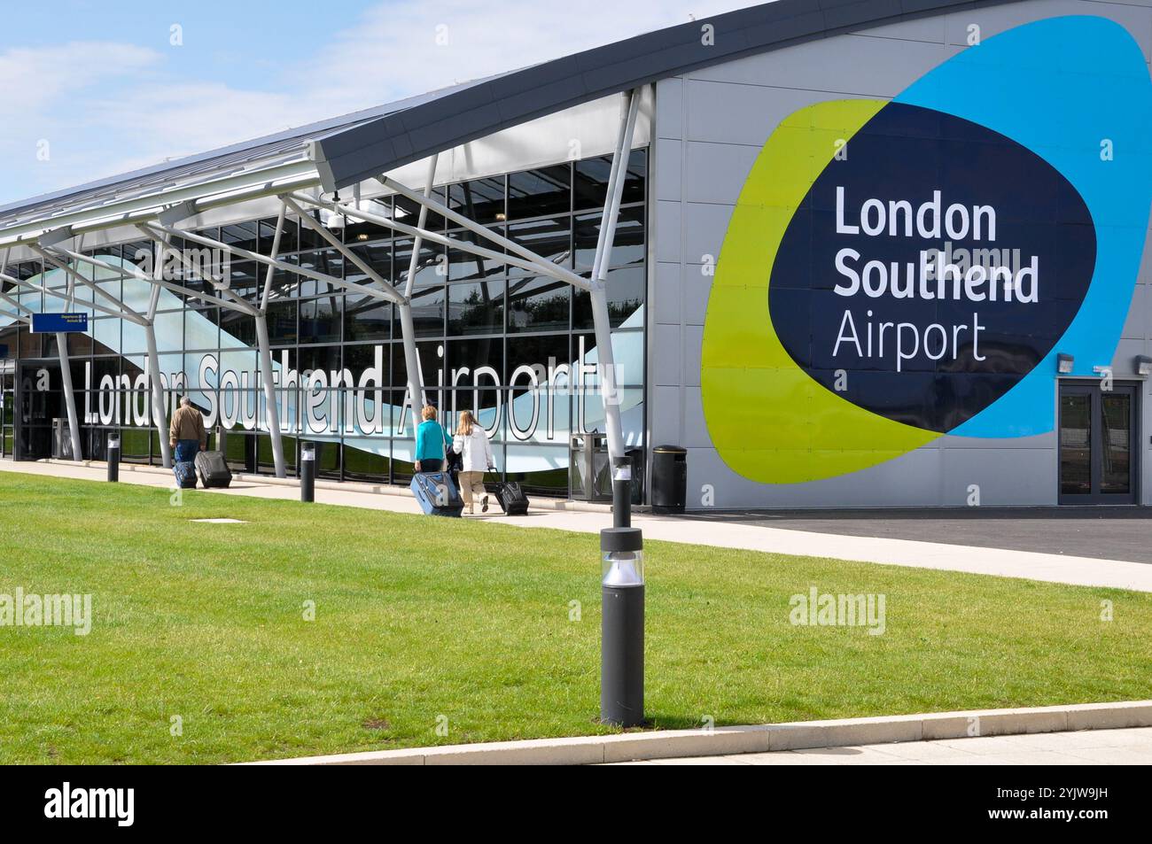 Aeroporto Southend di Londra. Passeggeri con bagagli diretti verso l'edificio del terminal, con logo London Southend Airport, simbolo Foto Stock