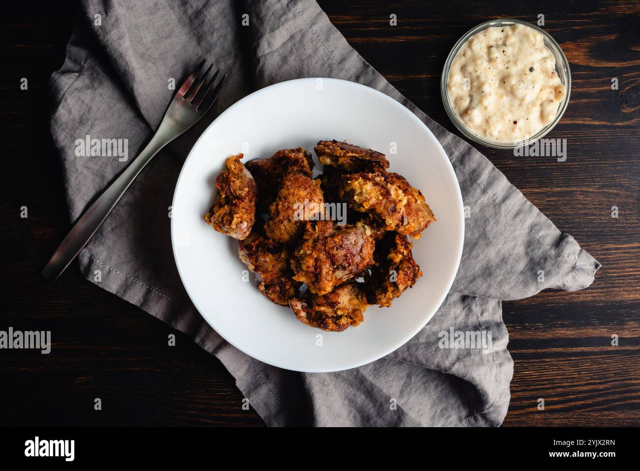 Fegati di pollo fritti con un piatto di sugo di carne: Fegati di pollo fritti e impanati con una ciotola di sugo di carne bianco pepato Foto Stock