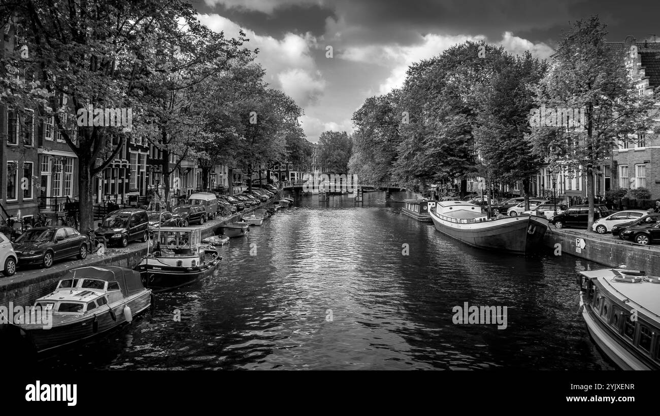 Foto in bianco e nero di un pittoresco canale nel centro storico di Amsterdam. I canali sono fiancheggiati da case secolari a spiovente. Foto Stock