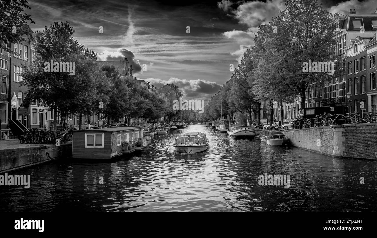 Foto in bianco e nero di un pittoresco canale nel centro storico di Amsterdam. I canali sono fiancheggiati da case secolari a spiovente. Foto Stock