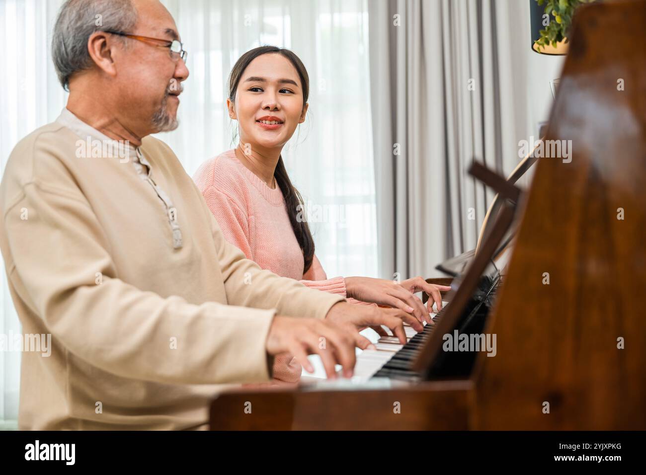 Felice figlia e padre anziano suonano musica al pianoforte insieme nel soggiorno Foto Stock