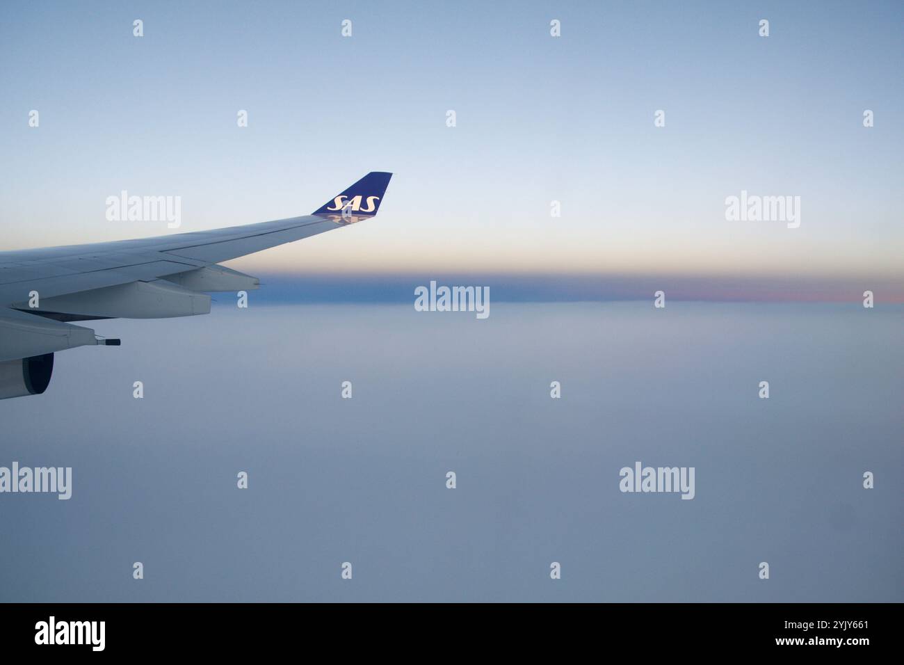 Above the Clouds, 24 novembre 2018: Vista del tramonto dalla finestra di un aereo con Long-Haul Aircraft Wing Foto Stock