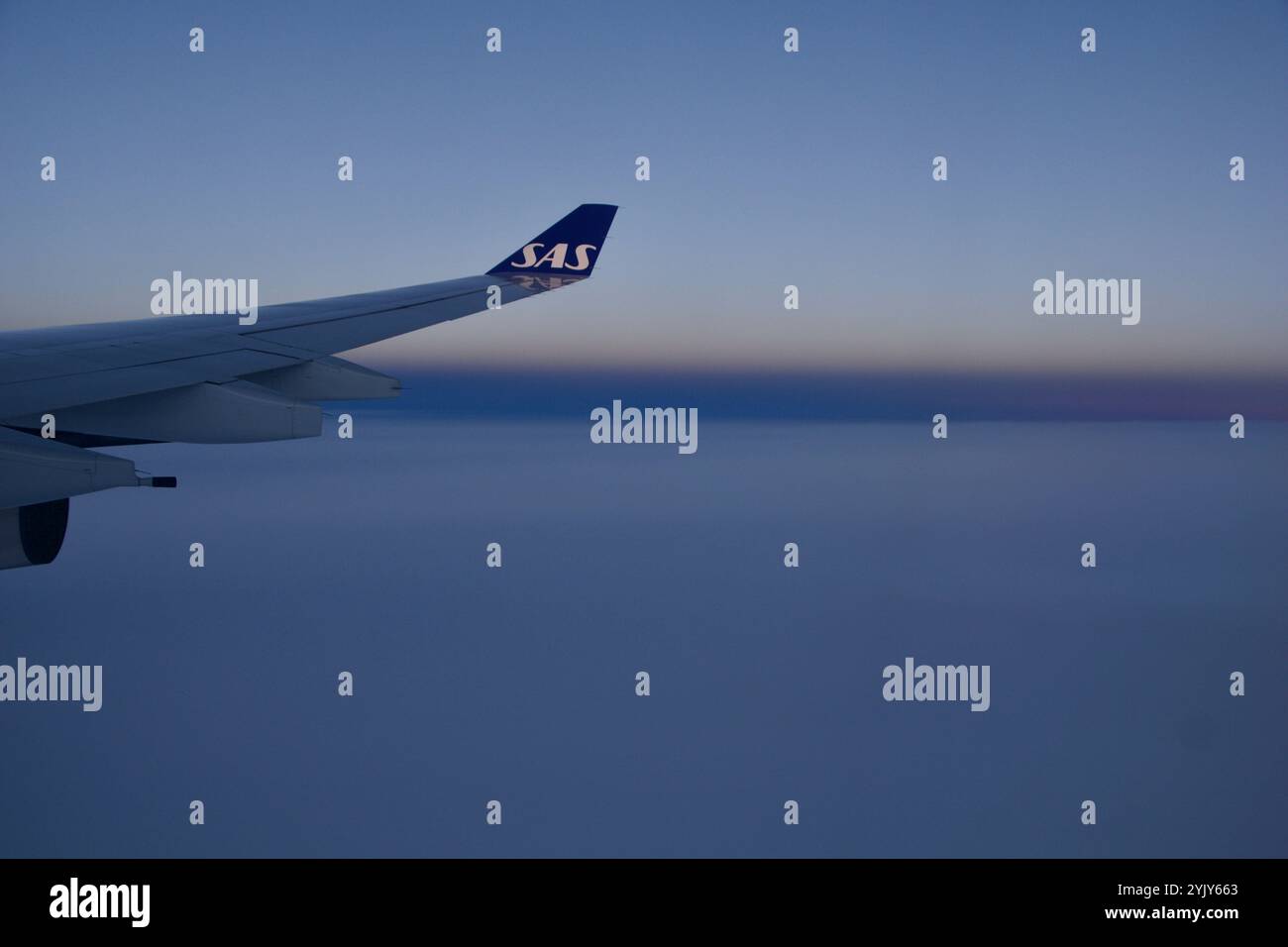 Above the Clouds, 24 novembre 2018: Vista del tramonto dalla finestra di un aereo con Long-Haul Aircraft Wing Foto Stock