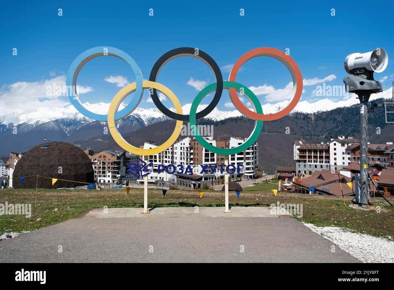 Gli anelli olimpici si esibiscono in una località di montagna che mette in mostra sport invernali a Sochi durante una giornata di sole chiaro - Rosa Khutor, Russia, 15 aprile 2023 Foto Stock