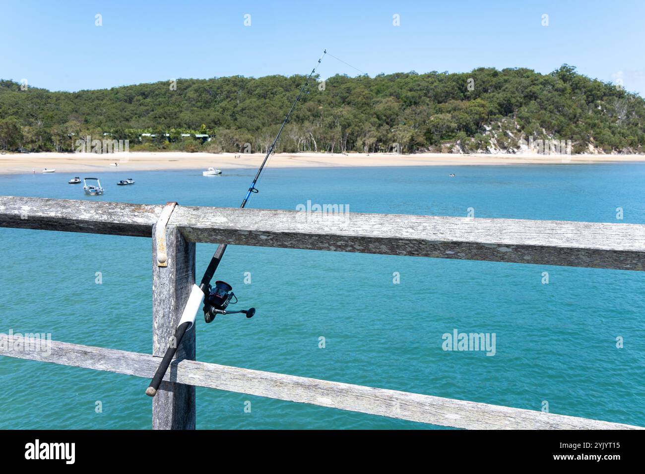Canne da pesca e mulinelli sul molo, l'isola K'gari Fraser, attività ricreative per pescare, vita sulla spiaggia costiera oceanica, hobby per anziani Foto Stock