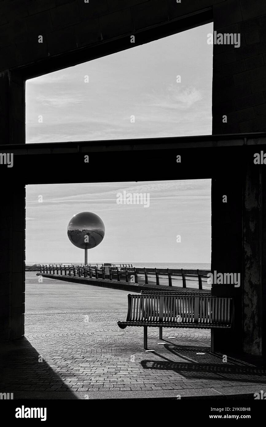 Riparo con panchina sulla South Promenade che incornicia una gigantesca scultura a specchio, Blackpool Regno Unito - Immagine stock catturata con smartphone
