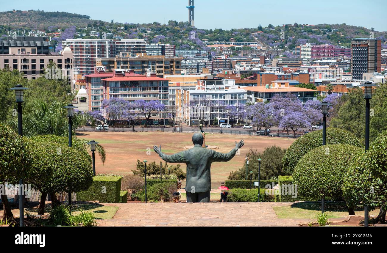Vista posteriore della statua di Nelson Mandela e del giardino degli Union Buildings, Pretoria, Sudafrica. Alberi di jacaranda in fiore sullo sfondo Foto Stock