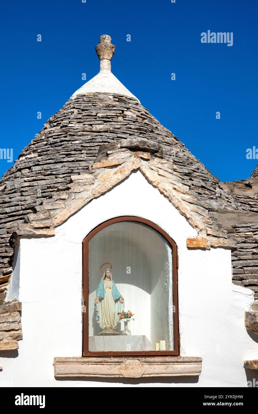 Un tradizionale trullo ad Alberobello, in Italia, con una statua votiva della Madonna Foto Stock