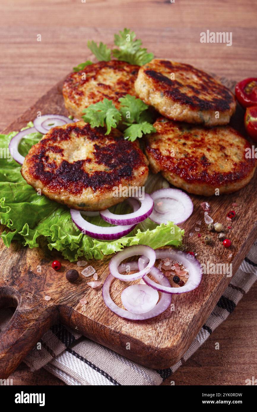Cotolette di pollo fritte, pollo tritato, con verdure, su un tagliere, con insalata di verdure, vista dall'alto, fatti in casa, nessuno Foto Stock