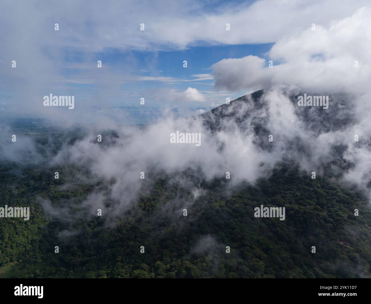 Lussureggianti montagne verdi sorgono sotto il cielo piene di nuvole alla deriva durante la serena atmosfera diurna. Foto Stock