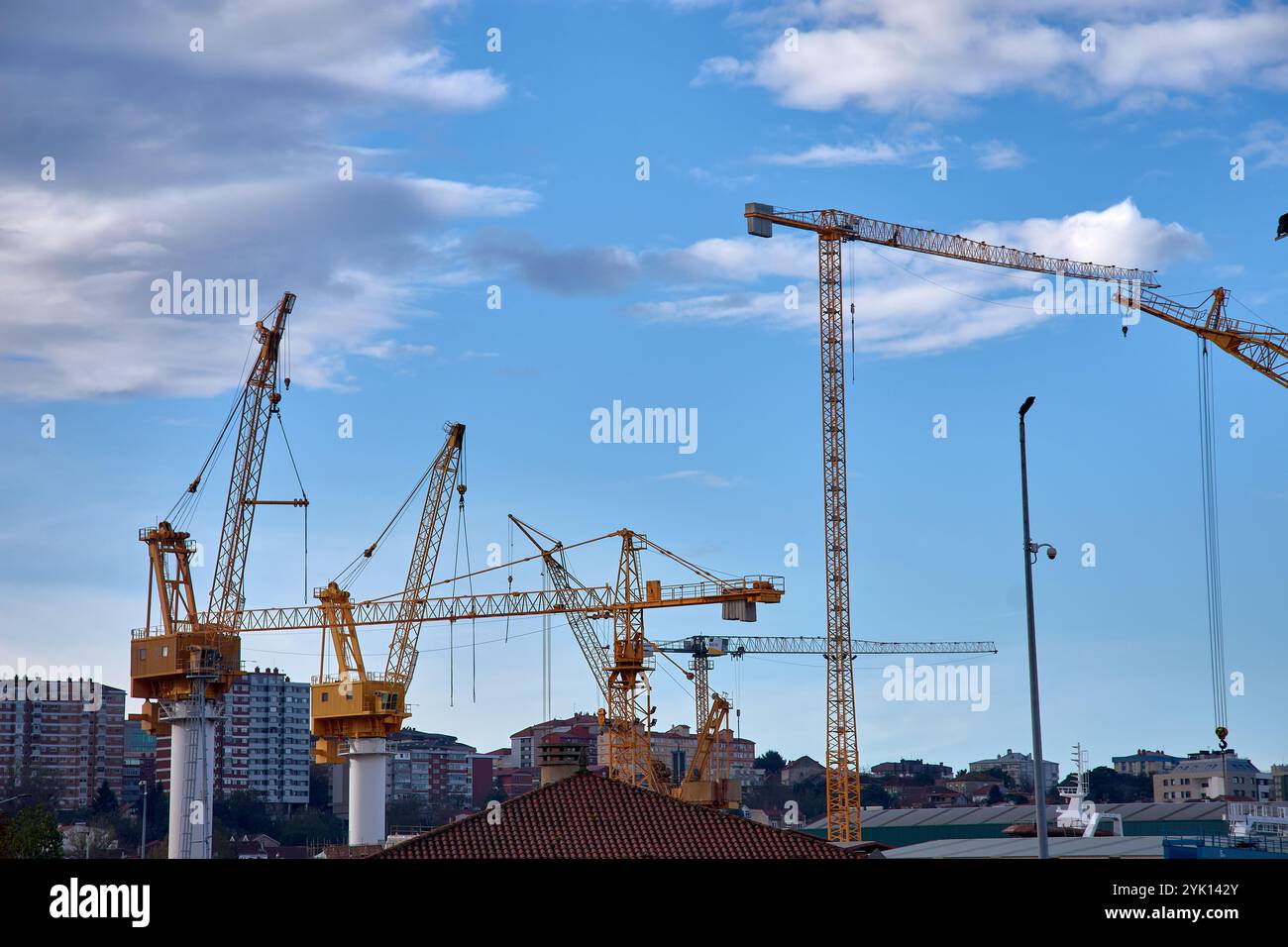 Gru industriali gialle nei cantieri navali di Vigo, Spagna, che torreggiano sui moli. Un simbolo vibrante dell'industria marittima della città e dell'attività portuale. Foto Stock