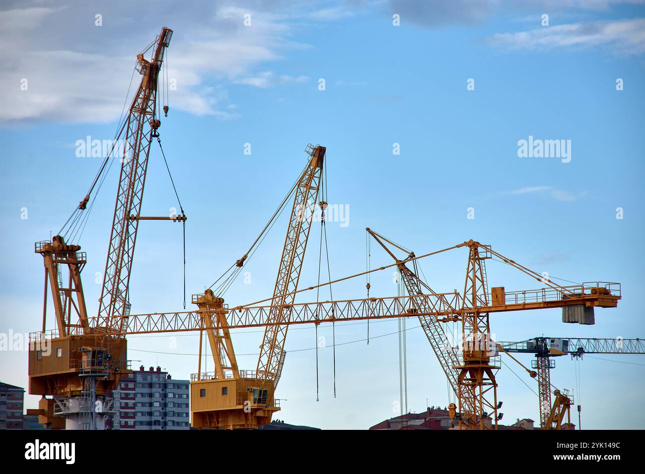 Gru industriali gialle nei cantieri navali di Vigo, Spagna, che torreggiano sui moli. Un simbolo vibrante dell'industria marittima della città e dell'attività portuale. Foto Stock