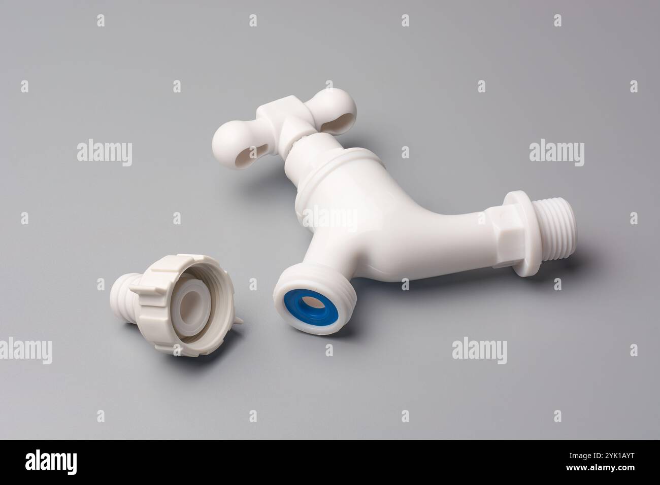 rubinetto in plastica bianca con manico a croce e connettore filettato sfondo grigio isolato, utilizzato in lavatrici o lavelli Foto Stock