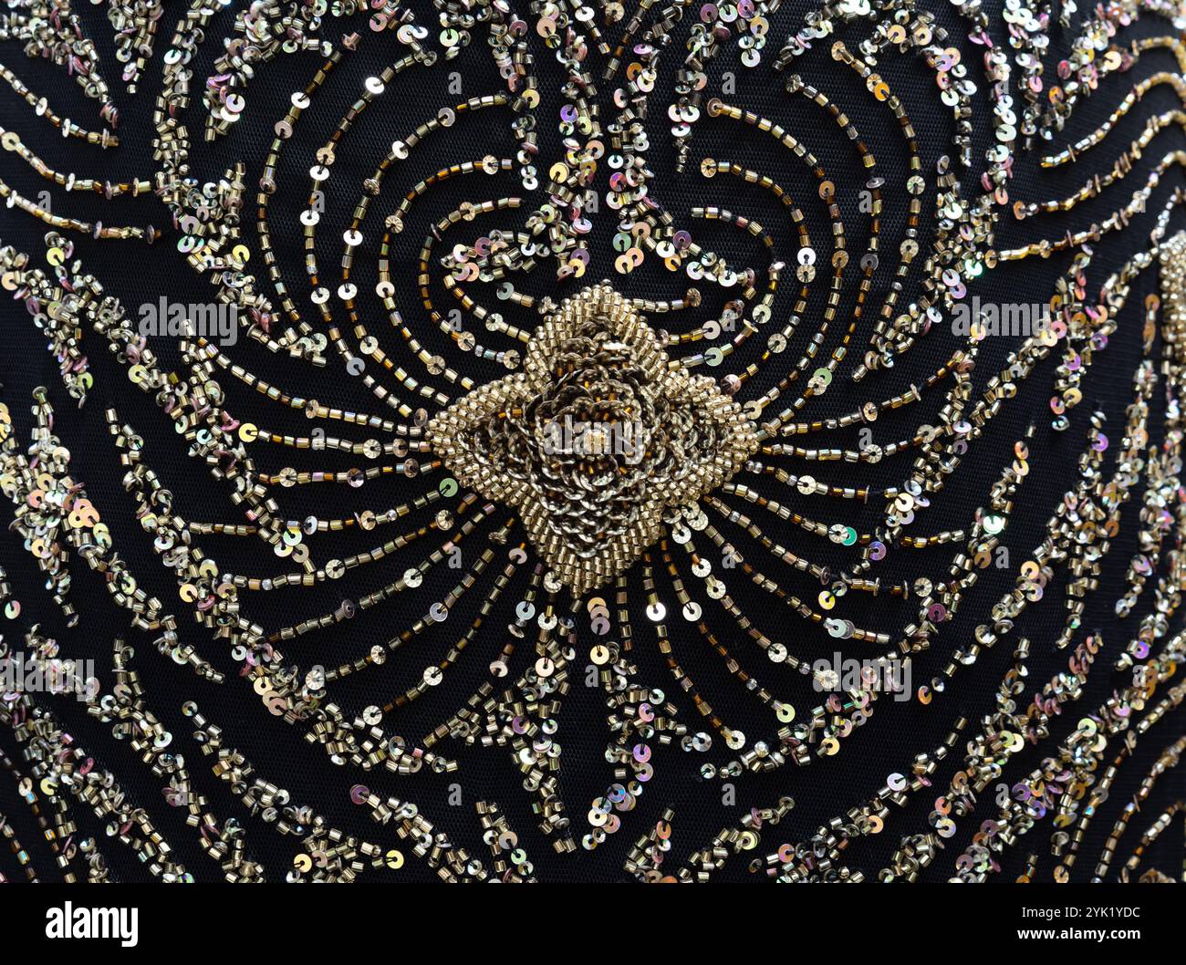 Paillettes dorate e decorazioni in perline su tessuto a rete nera. Elemento di un abito da sera. Foto Stock
