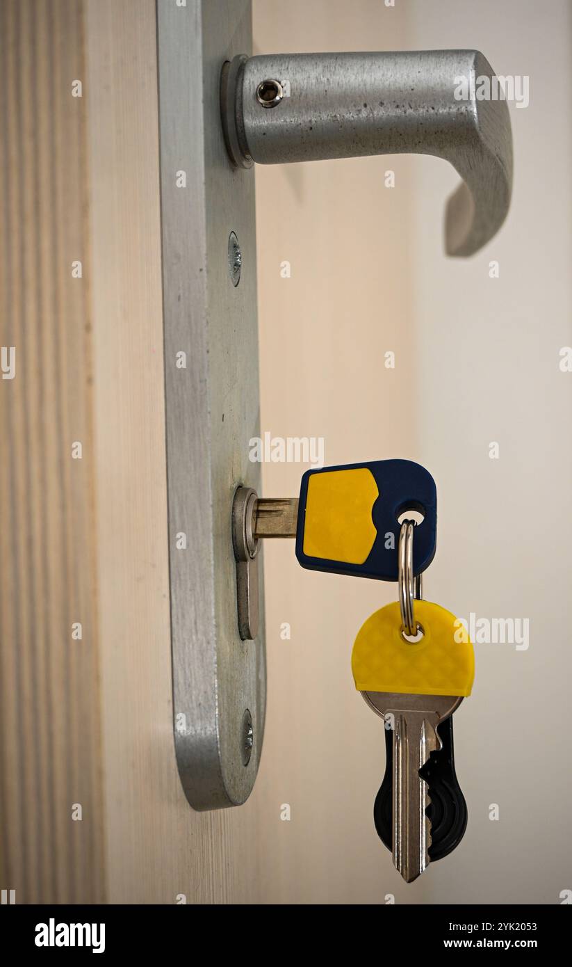 Chiavi inserite in una serratura della porta, che simboleggiano la sicurezza, l'accesso e la privacy in ambienti residenziali o commerciali. Foto Stock