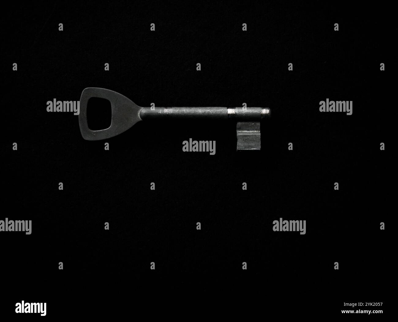 Chiave metallica su sfondo scuro che rappresenta la sicurezza, la privacy e la risoluzione dei problemi. Foto Stock