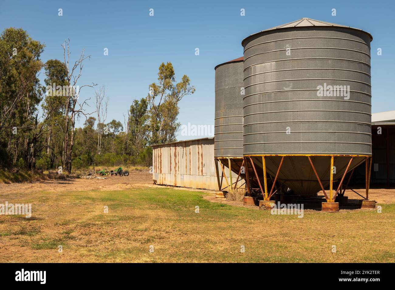 Scenario paesaggistico di attrezzature agricole e silos di stoccaggio dei cereali metallici nell'entroterra australiano. Foto Stock