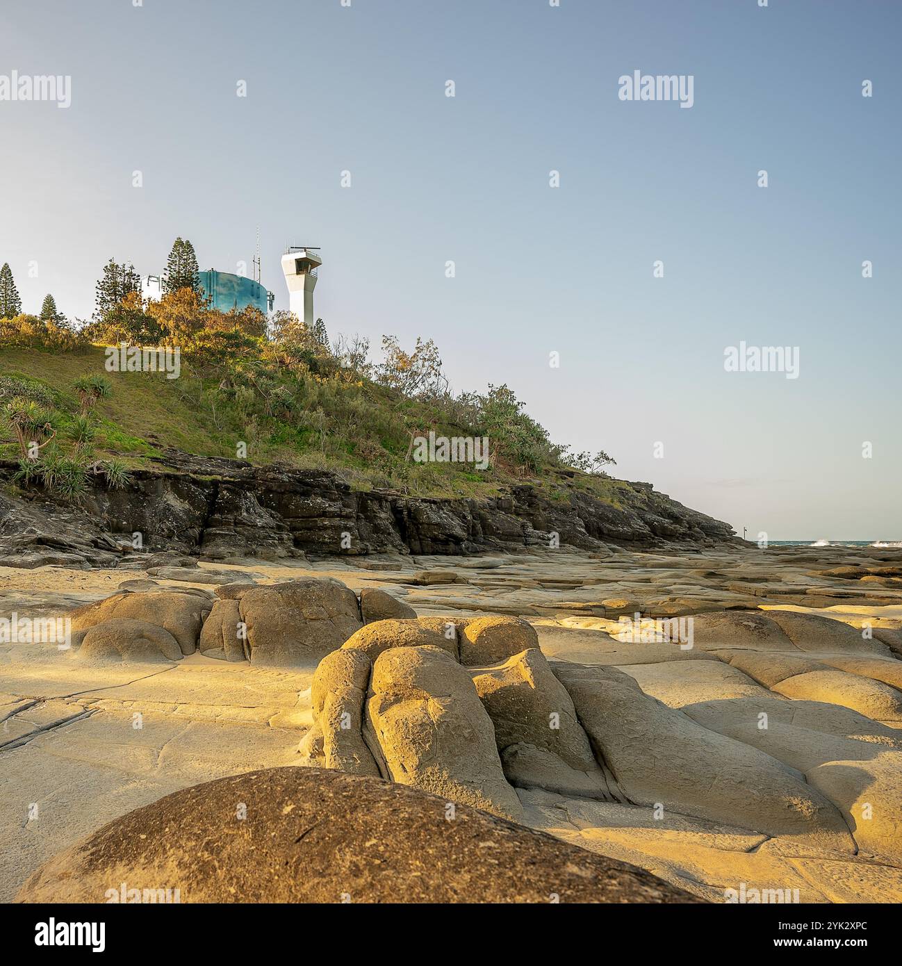 Punta Cartwright Headland nel tardo pomeriggio, mentre il sole tramonta ad ovest, faro, serbatoio d'acqua, parete rocciosa e piattaforma rocciosa Foto Stock