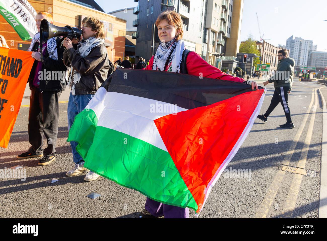 Leeds, Regno Unito. 16 NOVEMBRE 2024. L'attivista detiene una bandiera palestinese sulla strada fuori dalla stazione degli autobus di Leeds poiché la domanda giovanile ha bloccato 2 strade nel centro di Leeds alla fine di una settimana di azioni pro Palestina in tutto il paese, dopo la seconda azione 3 degli attivisti sono stati effettivamente banditi dal centro della città in quanto sono stati emessi con ordini S34/S35 e scortati ai margini della città. Credito Milo Chandler/Alamy Live News Foto Stock