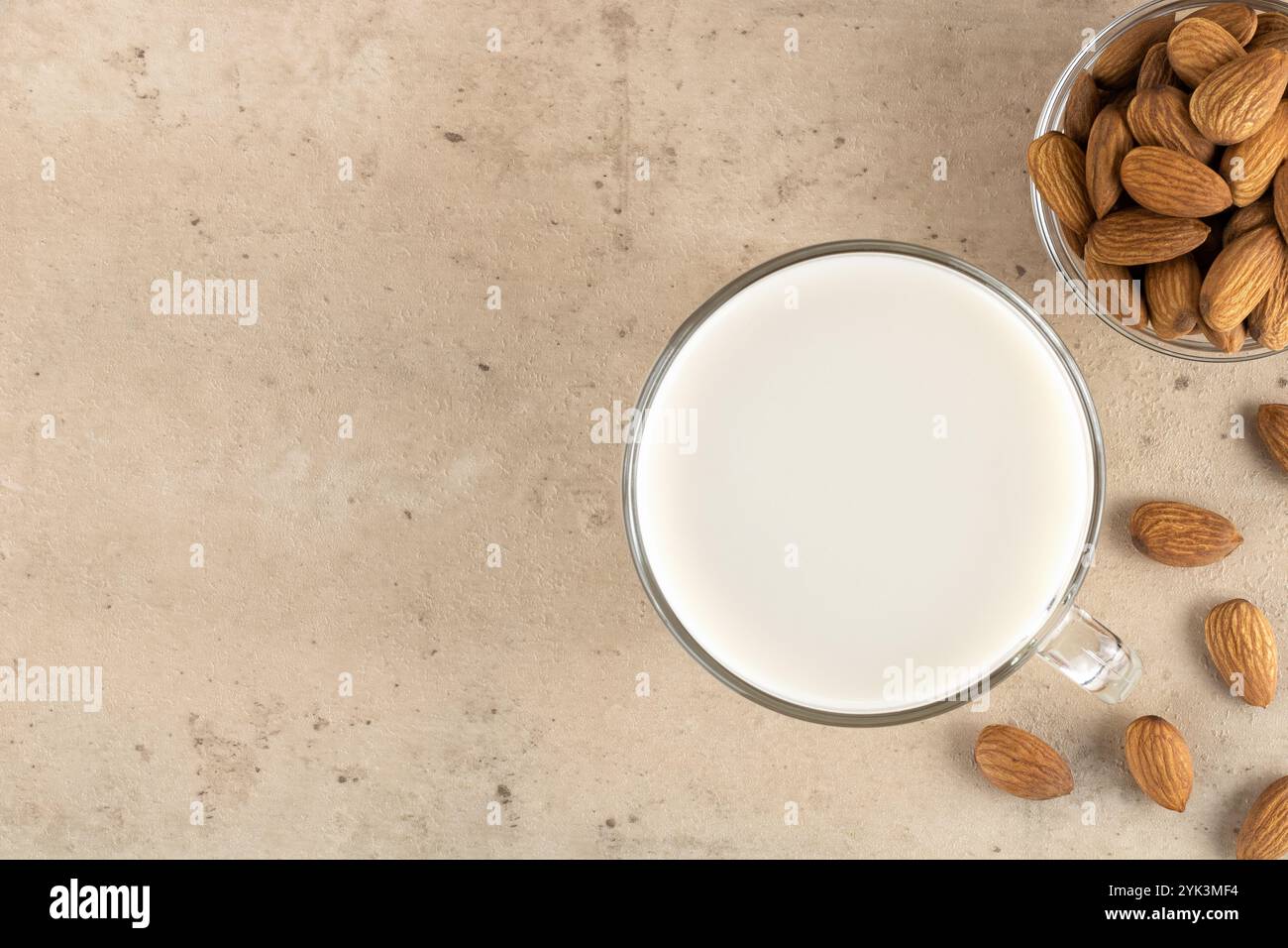 Latte di mandorla in un bicchiere su sfondo beige. Vista dall'alto. Copia spazio. Messa a fuoco selettiva. Latte di noci privo di lattosio. Foto Stock